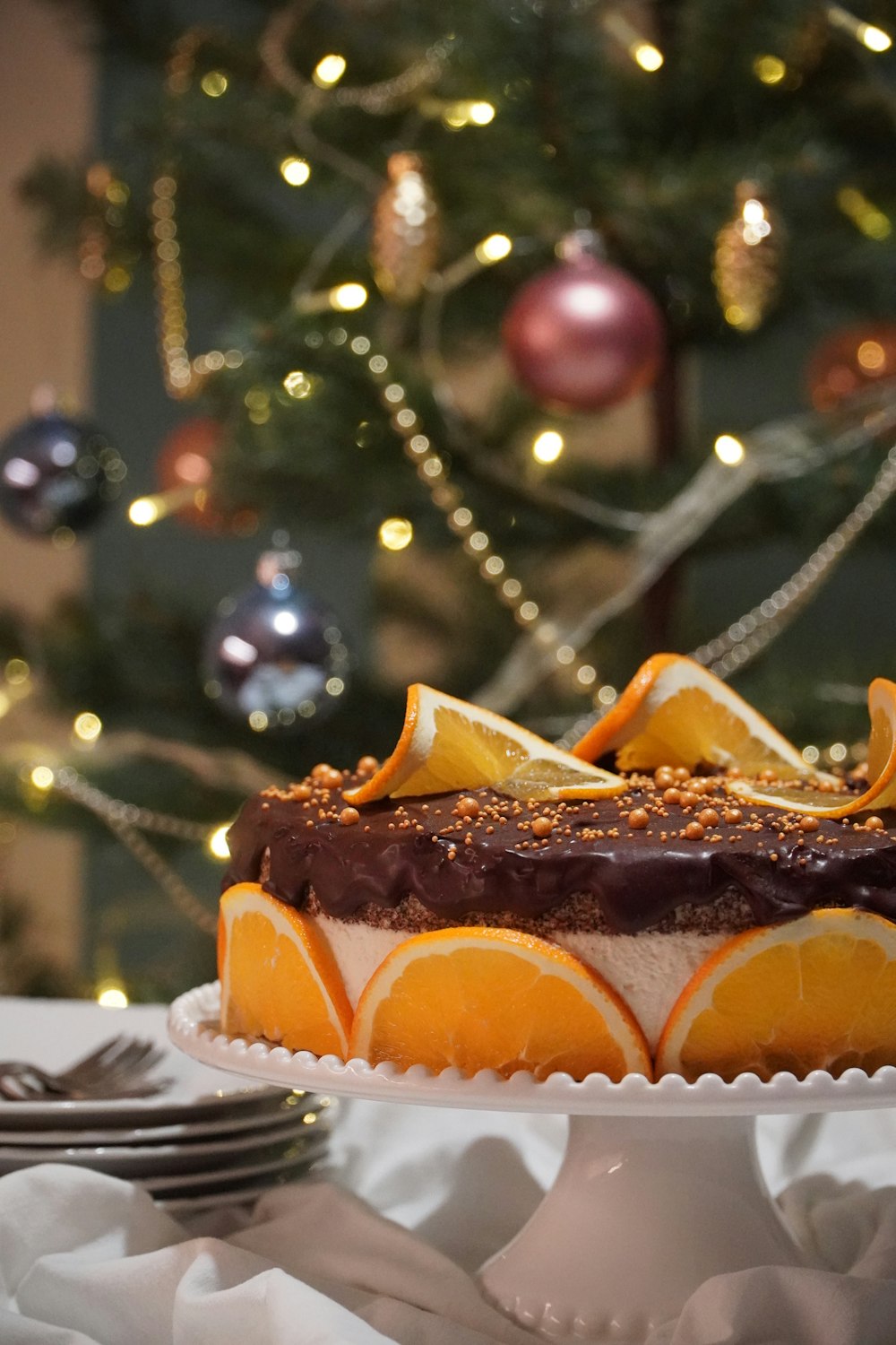 a cake sitting on top of a white plate next to a christmas tree