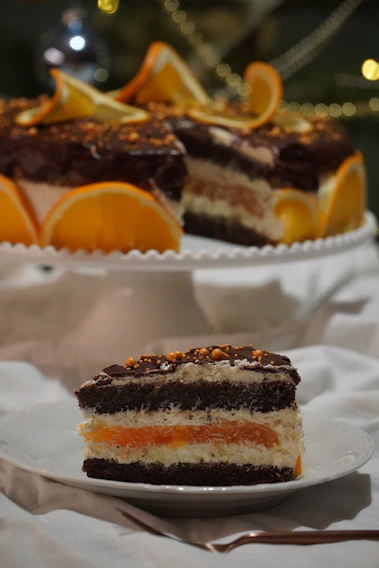 A close-up of a decadent flourless chocolate orange cake with delicate gold accents on a pastel pink plate.