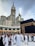 A large group of people, many dressed in white robes, are gathered around the Kaaba, a black cube structure adorned with golden details. The towering Abraj Al Bait Clock Tower is visible in the background, with its large clock and decorative spire. The scene conveys a sense of a spiritual gathering.