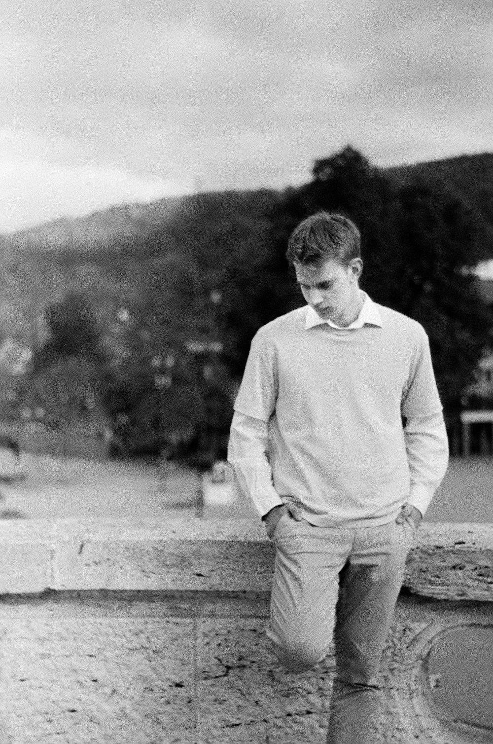 a young man leaning against a stone wall