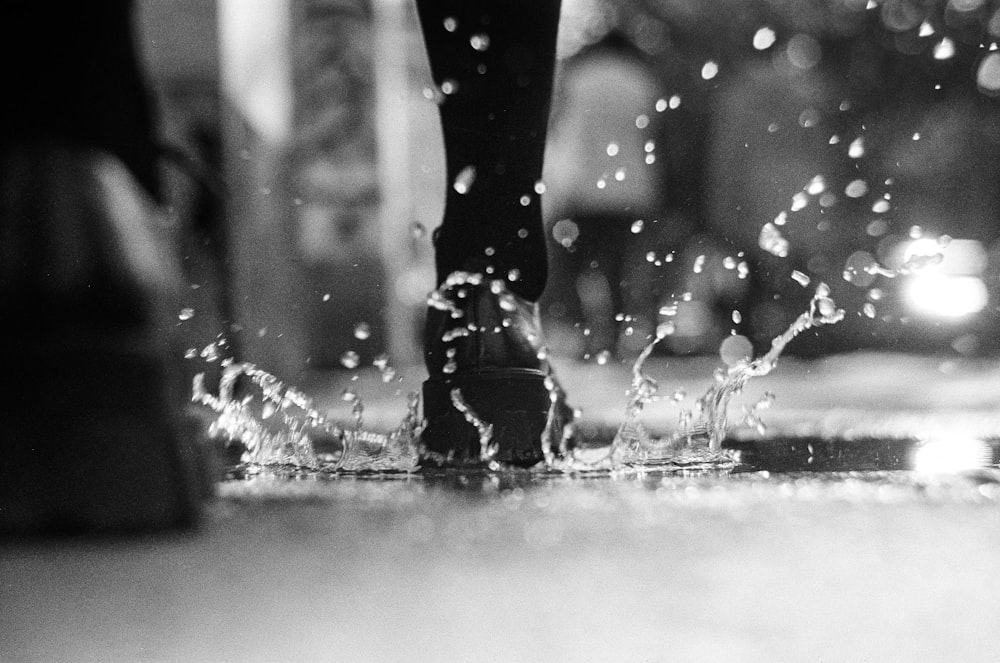 a black and white photo of a person walking in the rain