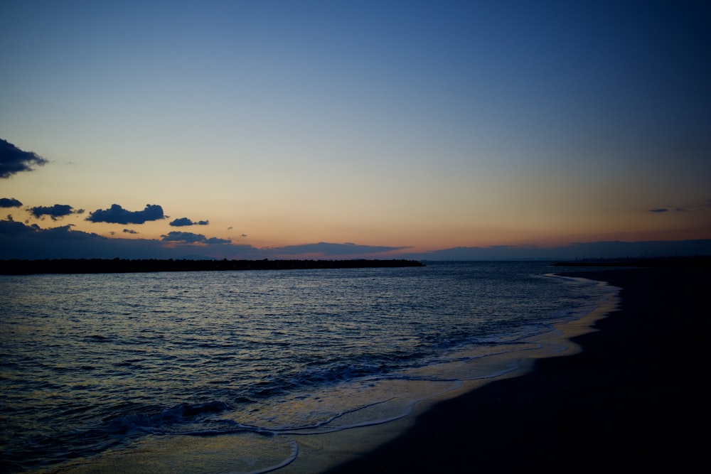 the sun is setting over the water at the beach