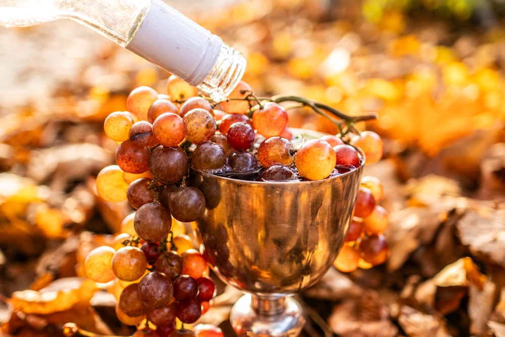 a person pouring wine into a cup filled with grapes