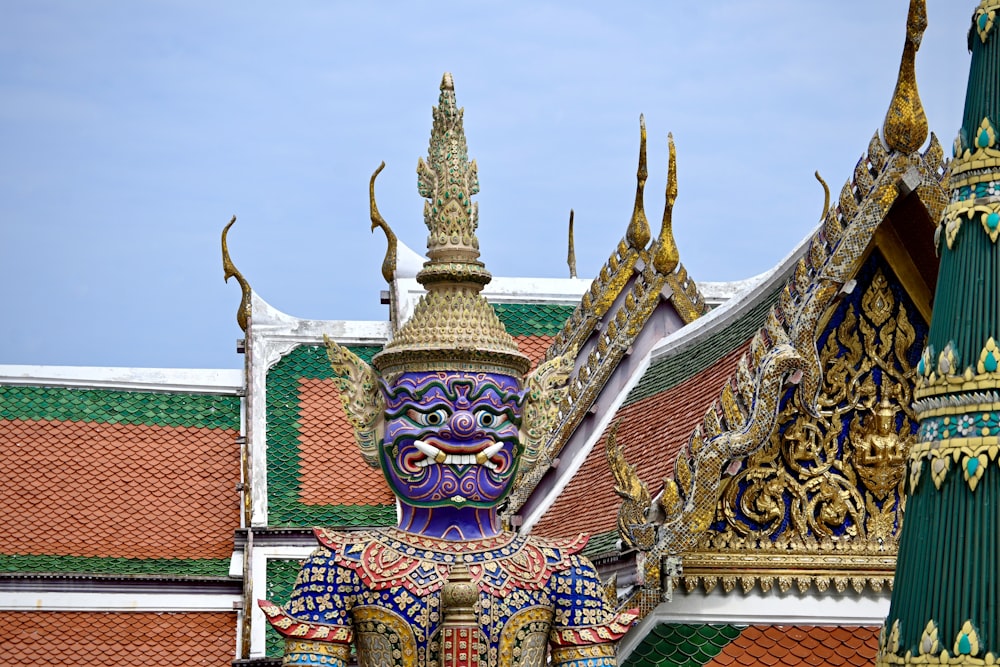 una statua di una persona con una maschera viola in cima a un edificio
