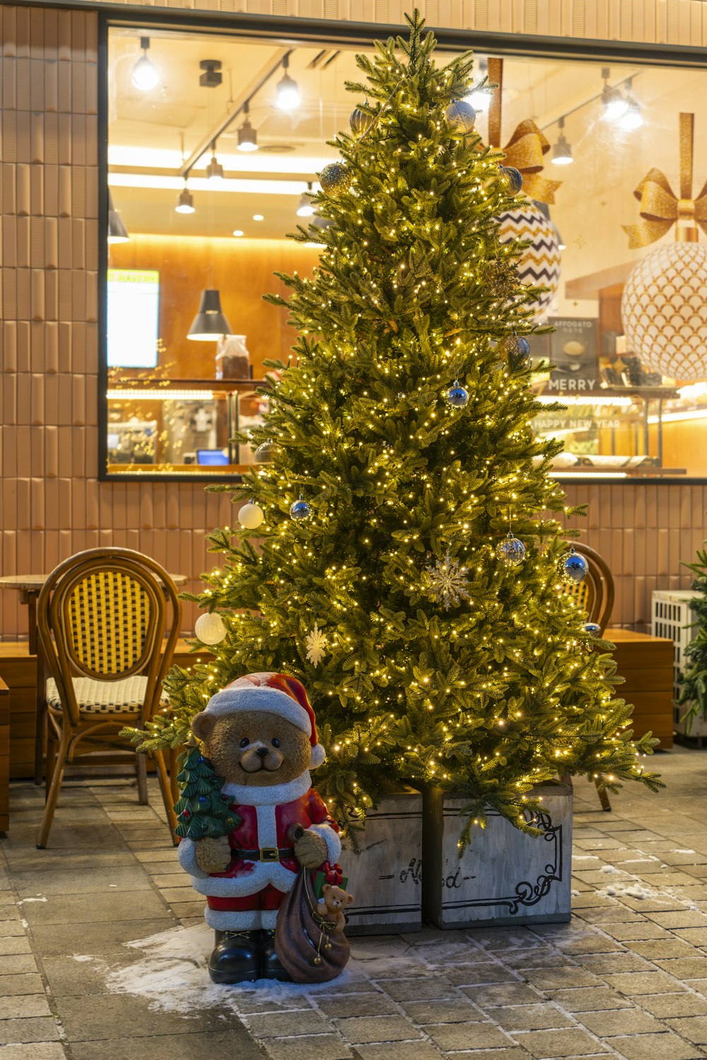 a teddy bear sitting next to a christmas tree