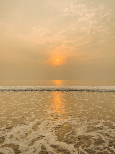 A serene beach at sunset with gentle waves lapping the shore.