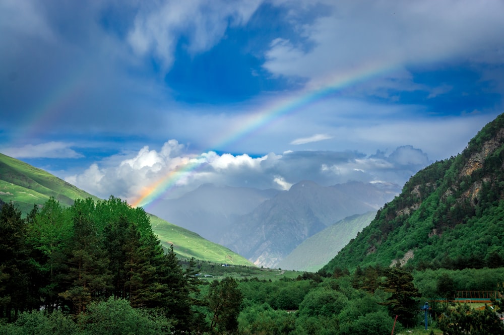a rainbow in the sky over a valley