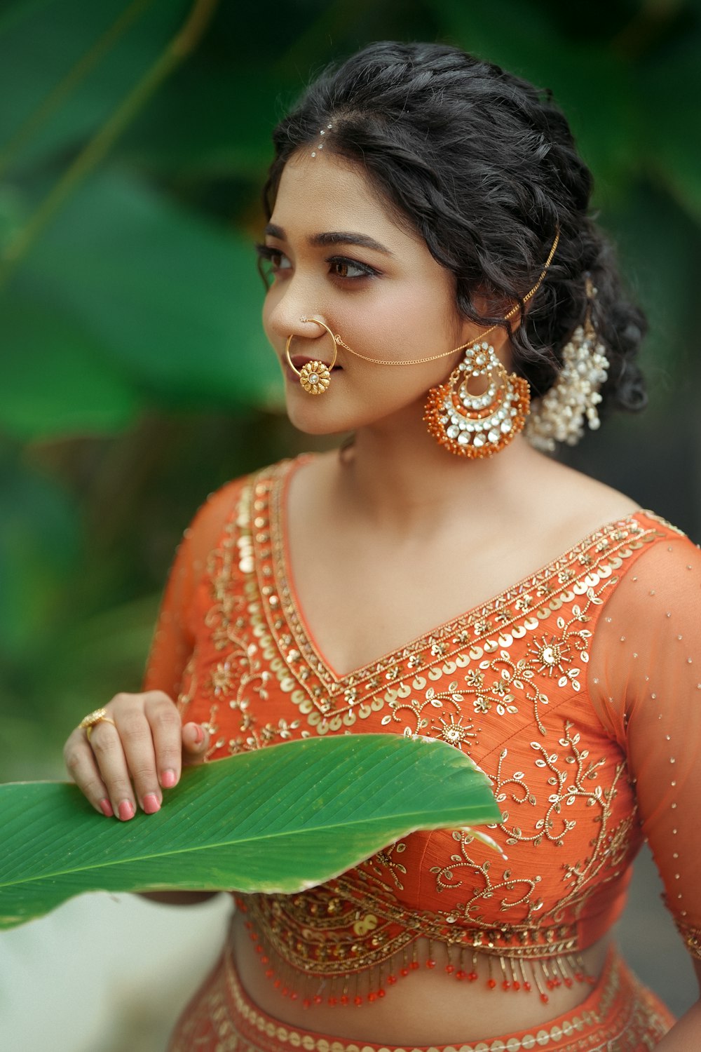 a woman in an orange outfit holding a green leaf