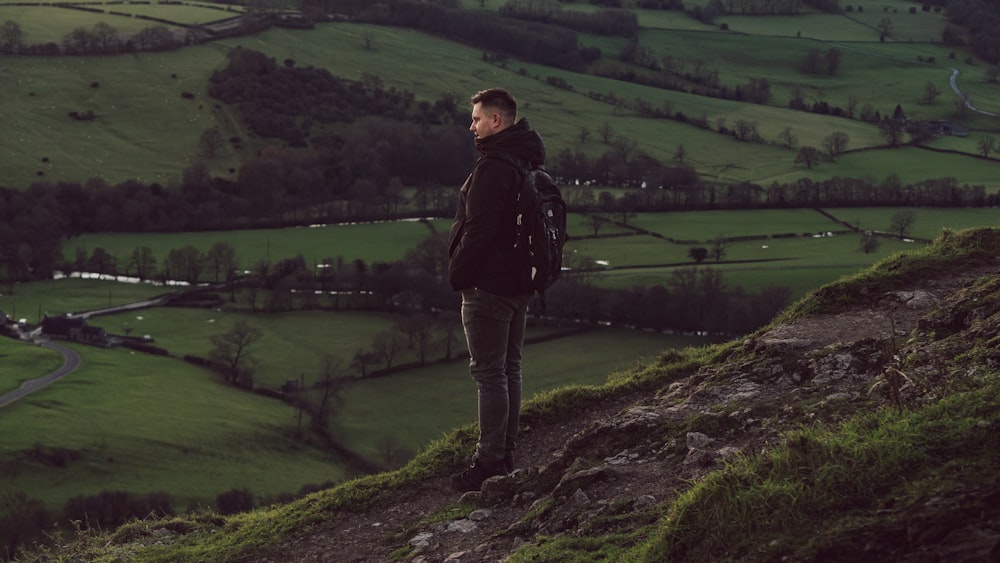 a man standing on top of a lush green hillside