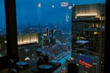 Nighttime cityscape seen through the large window of the modern city room, city lights glowing.