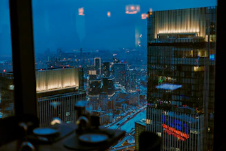 Night city skyline viewed from an office window, hinting at late-night hustle.
