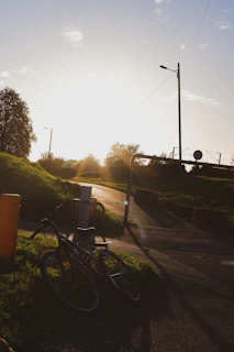 Sunset casting golden light on a nobbytrail bike resting against a weathered wooden fence on a trail ridge