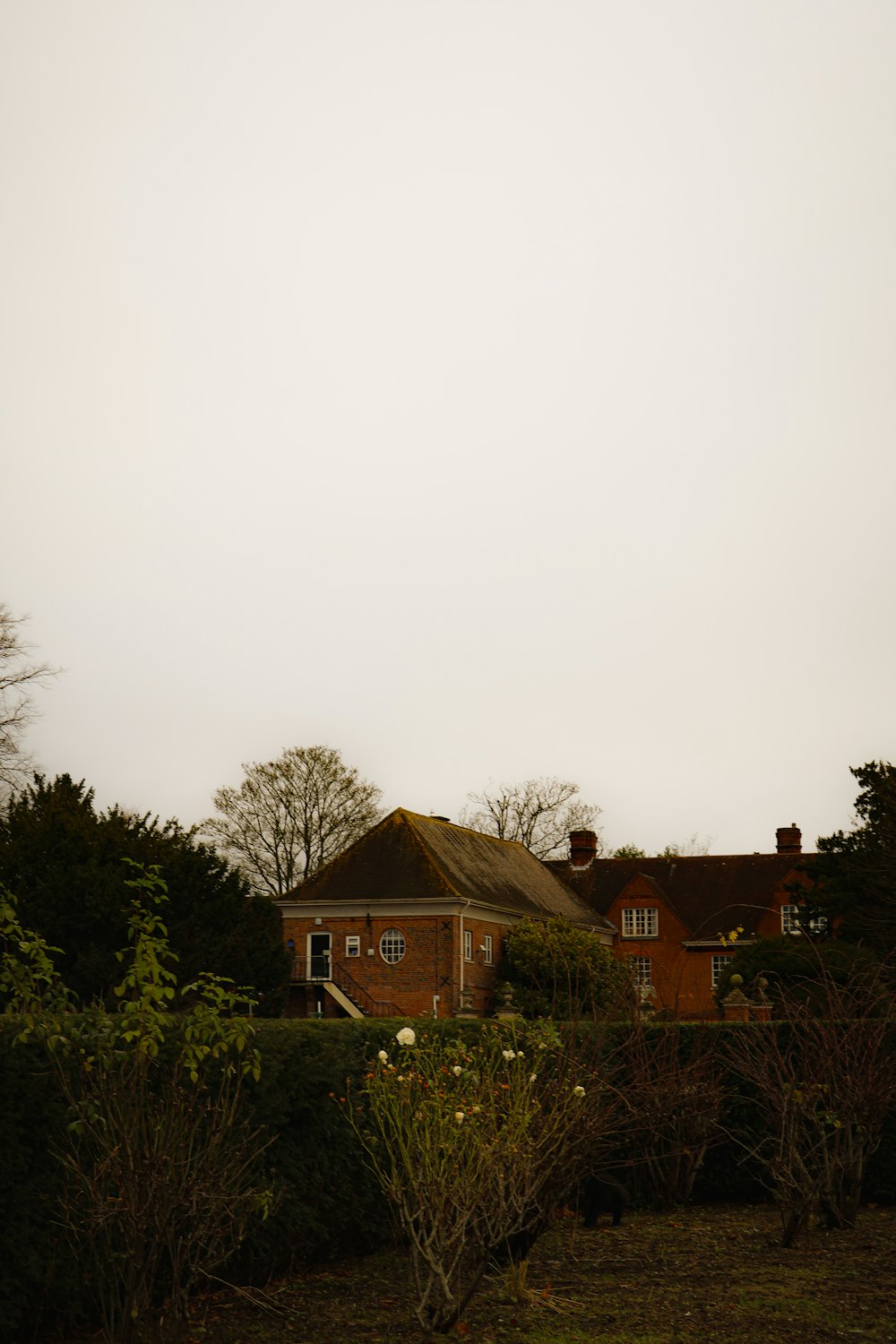 a red brick house surrounded by trees and bushes