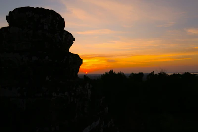 A panoramic view of a towering megalithic structure silhouetted against a vibrant sunset sky.