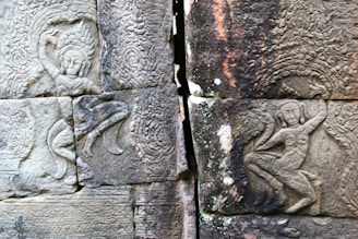 Ancient stone carvings display intricate, detailed figures with elaborate headdresses and traditional poses, set within textured surfaces that showcase artistic skill and cultural significance.