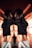 A person wearing a black cropped top and white Calvin Klein underwear is positioned back-to-back against a mirror, creating a symmetrical reflection. The lighting casts warm, orange-toned shadows and lines across the scene, creating a dramatic visual effect.