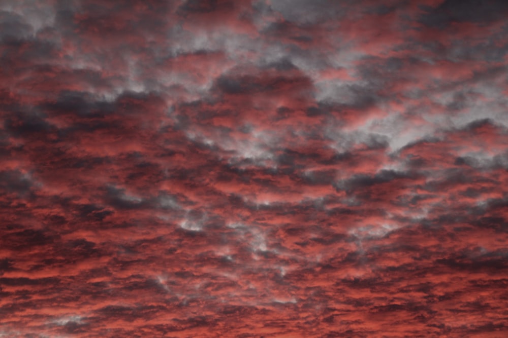 a red sky with clouds and a plane in the foreground