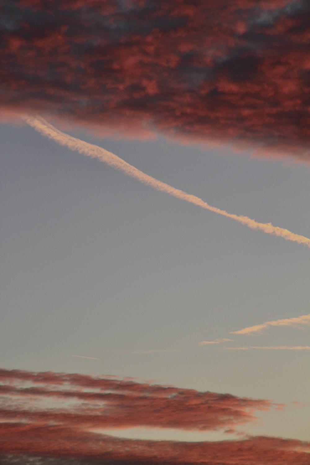 a plane flying through a cloudy sky with contrails in the sky