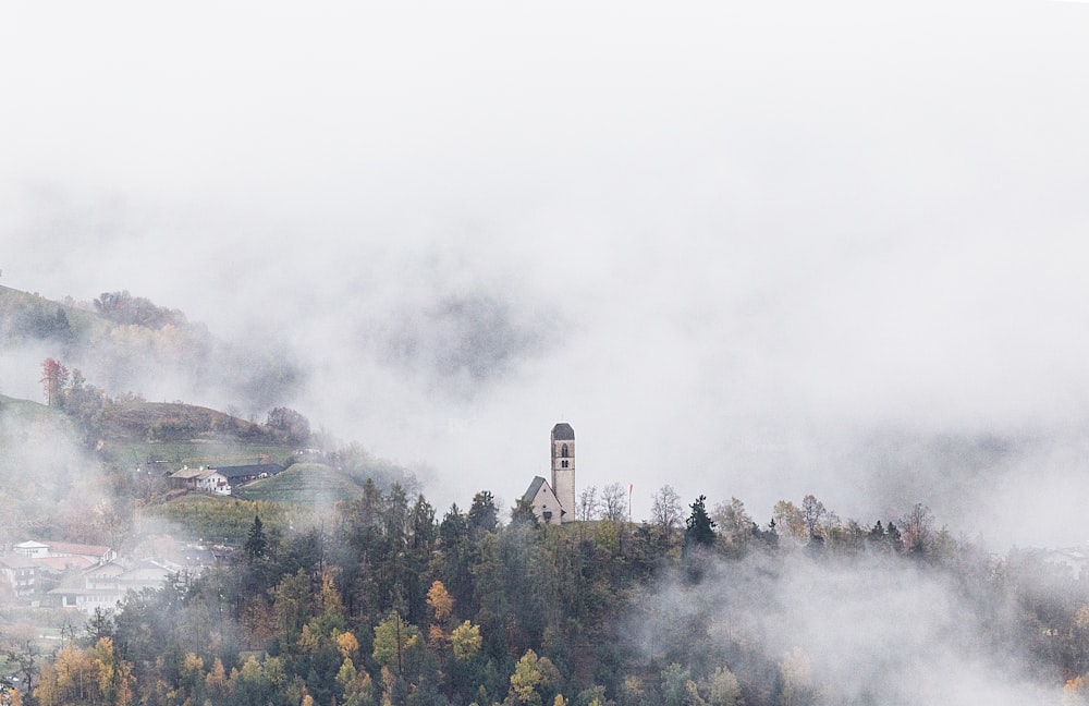 a foggy mountain with a clock tower in the distance