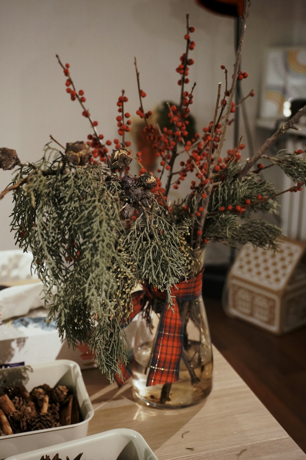 a vase filled with branches and berries on a table