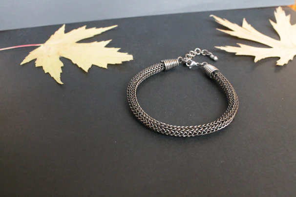 Close-up of a handmade men's bracelet resting on a rustic wooden campfire bench