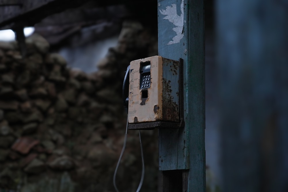 an old phone is attached to a wooden pole