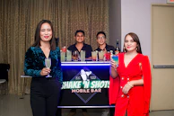 An intimate bachelorette party scene with guests laughing around a chic, collapsible bar setup.