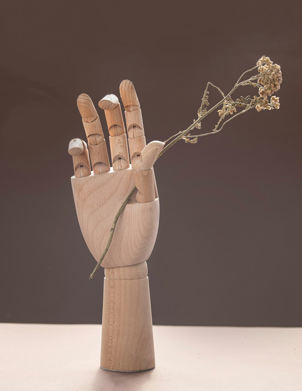 a wooden sculpture of a hand holding a flower