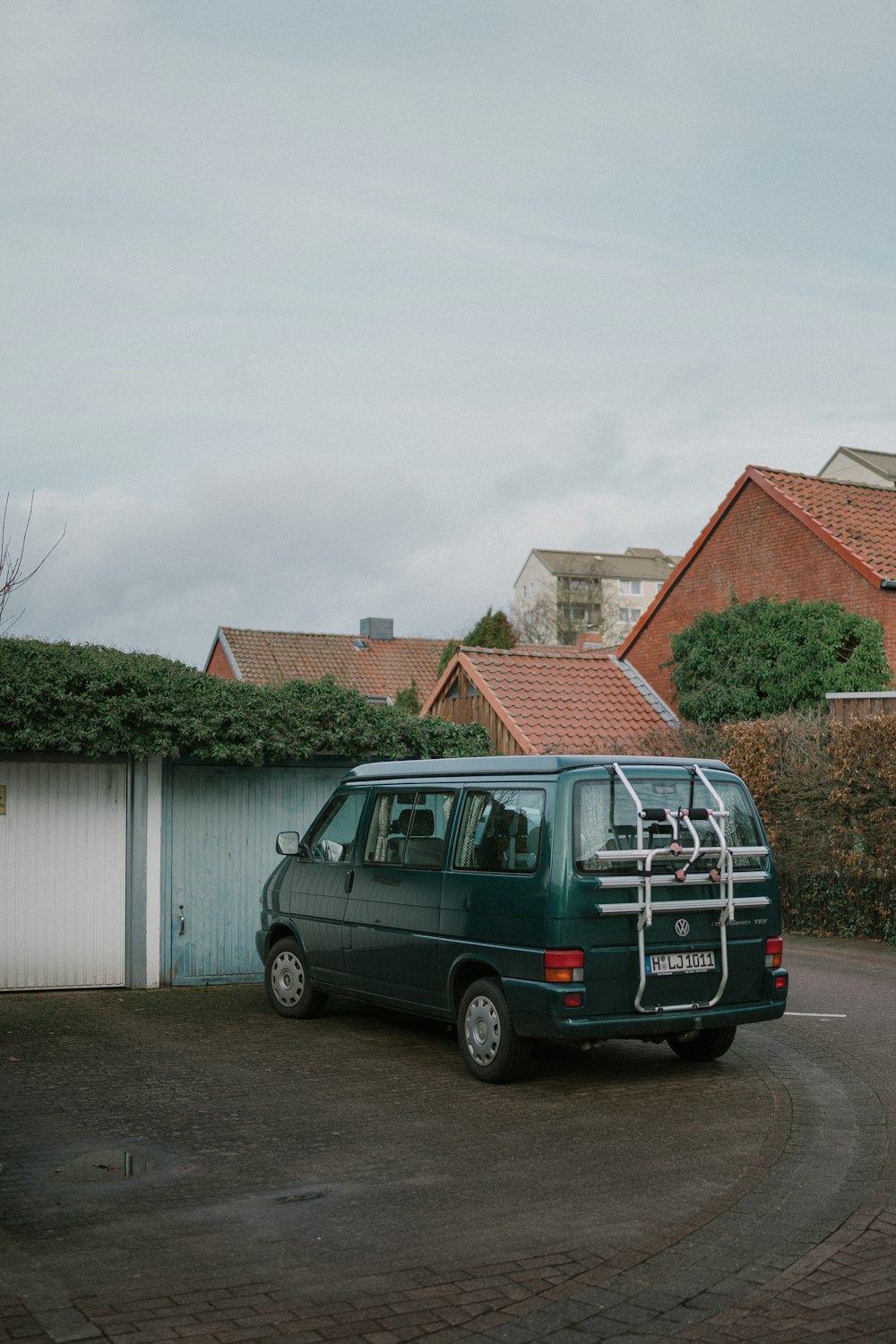 a green van parked in a driveway next to a house