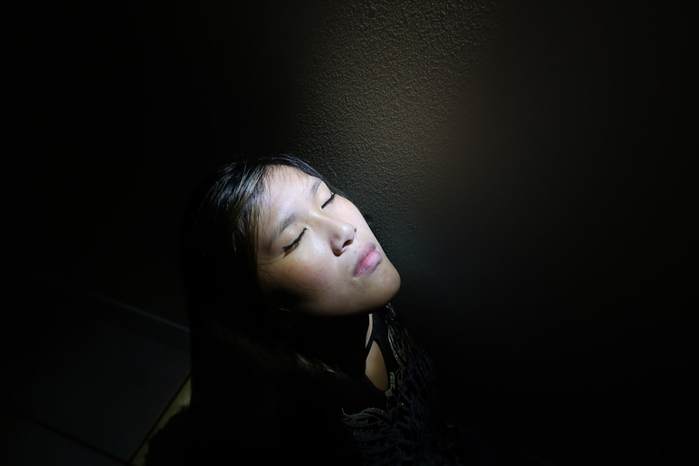 a woman with her eyes closed in the dark