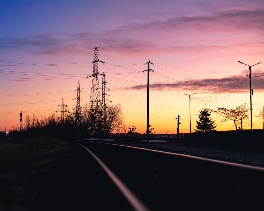 a train track at sunset with power lines in the background