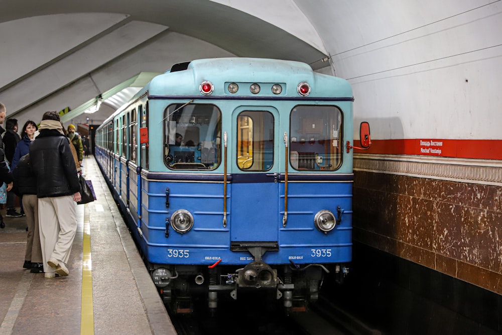 a blue train pulling into a train station