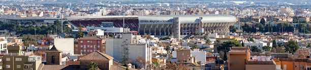 A scenic view of a European city skyline with a football stadium in the distance.