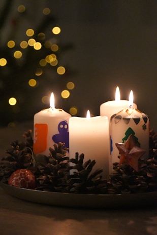 Seasonal holiday candles arranged on a rustic shelf with pinecones and soft fairy lights.