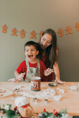 a woman and a child are making christmas cookies