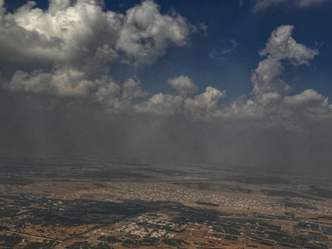 A sweeping aerial view of vast Texas farmland under a cloudy sky, emphasizing scale and story.