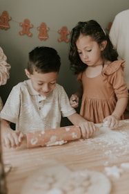 Two boys happily baking together, flour-covered hands mixing dough in a sunlit kitchen.