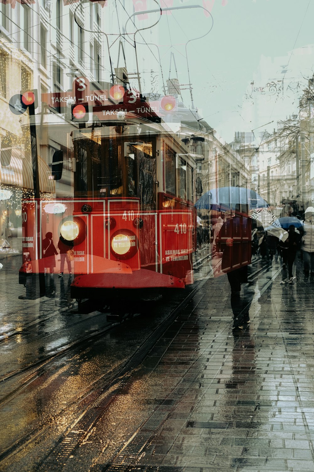 a red trolley car traveling down a rain soaked street