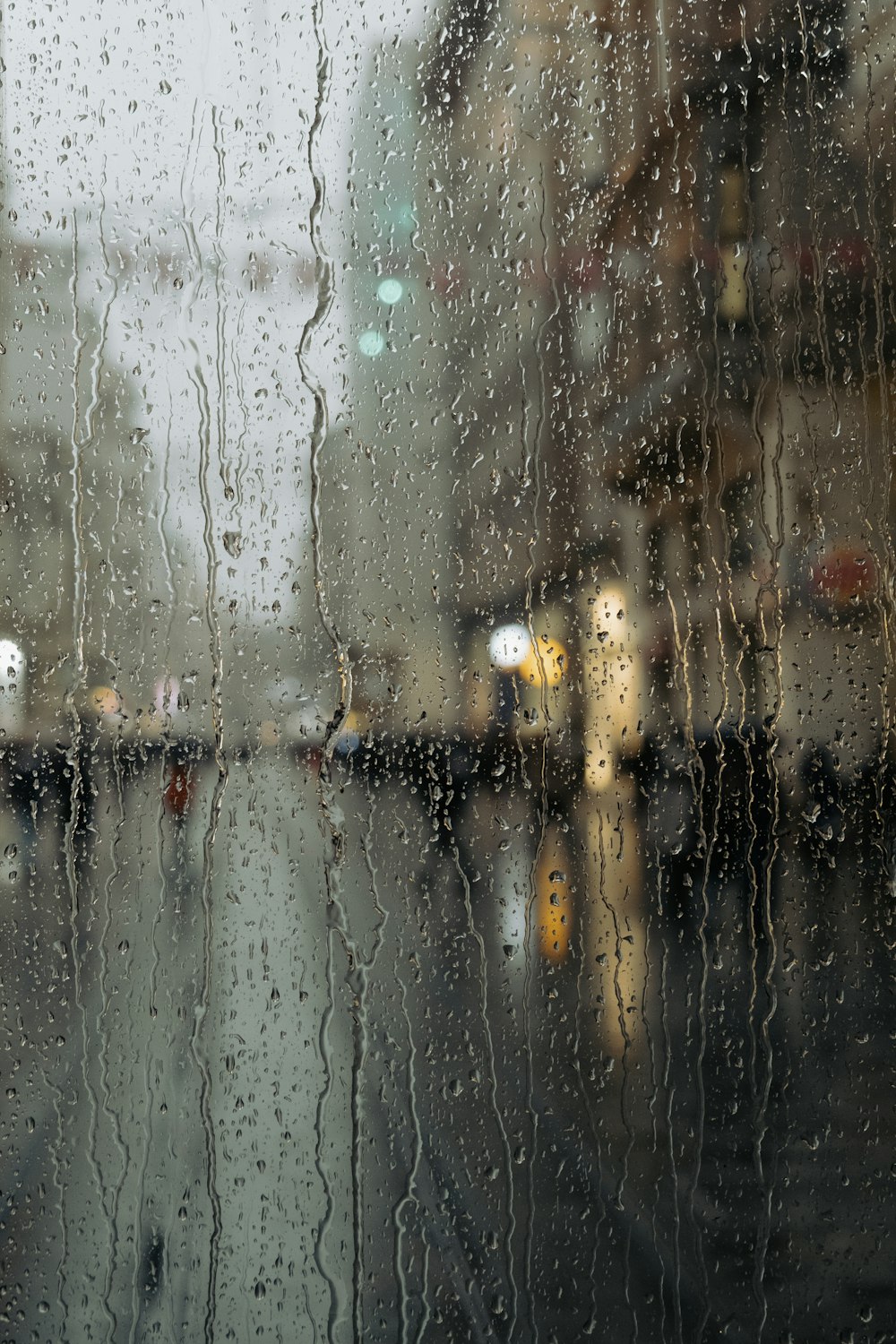 雨に濡れた窓越しに街並みを望む