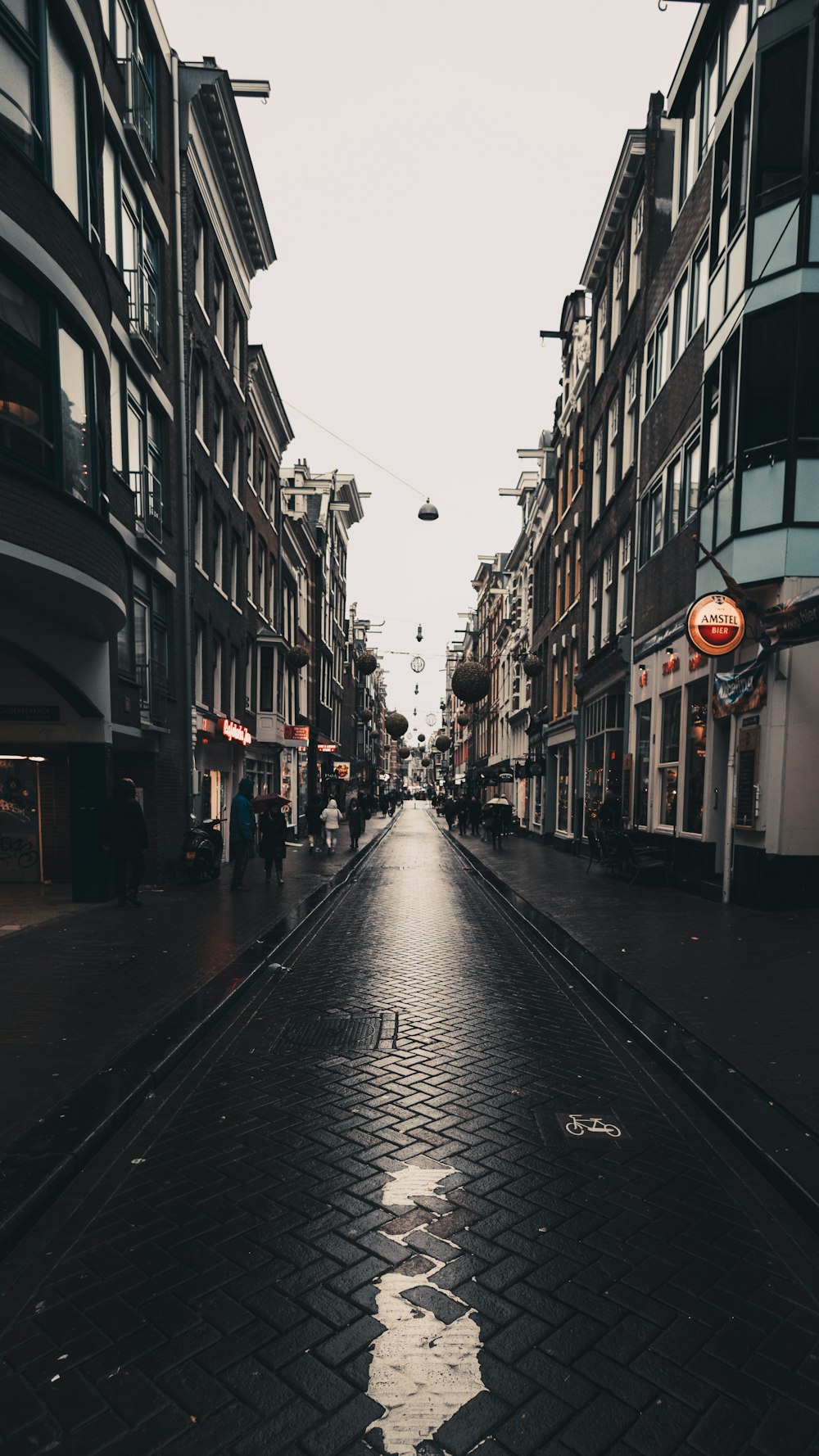 a wet street with people walking down it