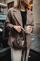 A lifestyle shot of a young woman enjoying a coffee break, her stylish handbag resting beside her.