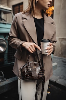 A lifestyle shot of a young woman enjoying a coffee break, her stylish handbag resting beside her.