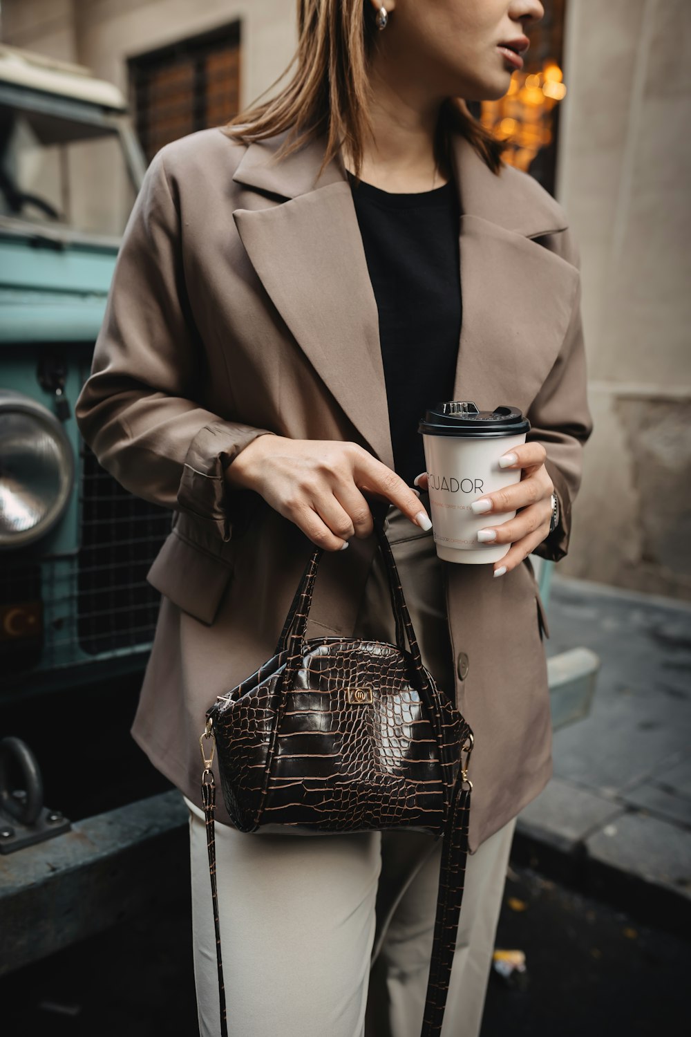 a woman holding a coffee cup and a purse