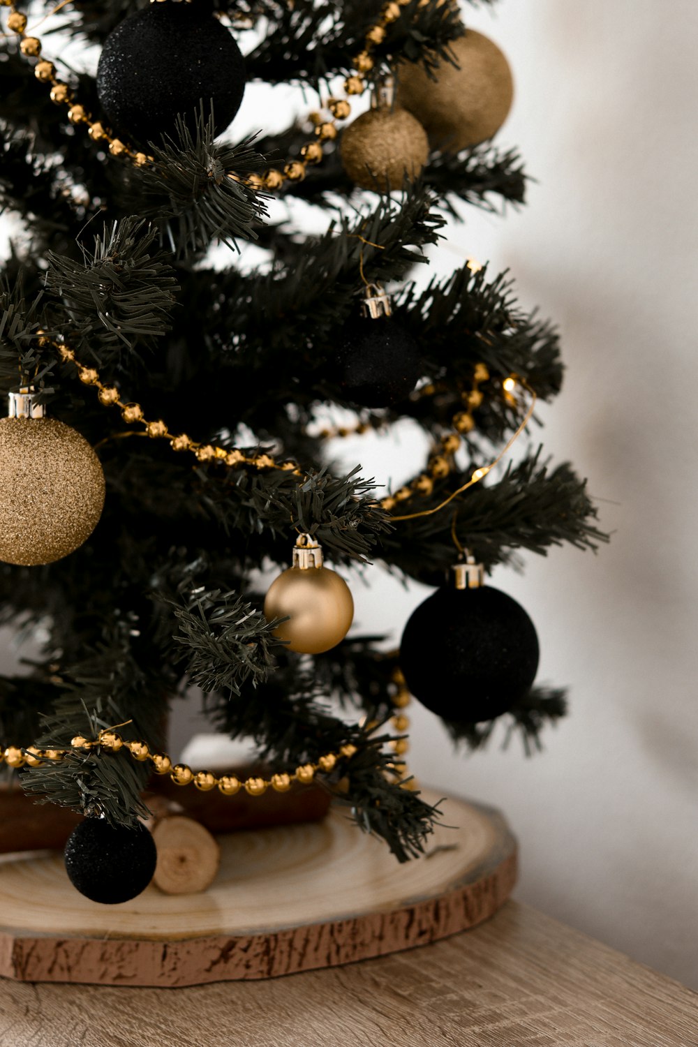 Un pequeño árbol de Navidad con adornos negros y dorados