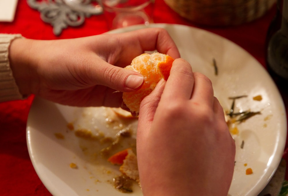 a person is peeling an orange on a plate