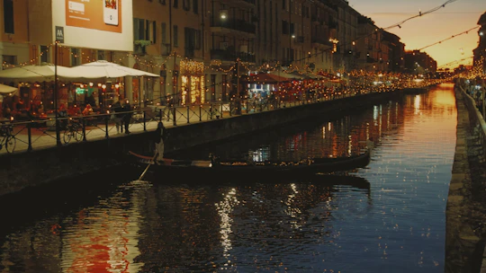 Evening lights reflecting on the Navigli district canals bustling with diners and nightlife.