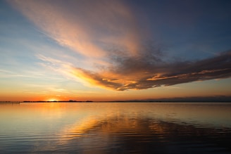 A sunset over calm waters, capturing the peaceful promise after emotional storms.