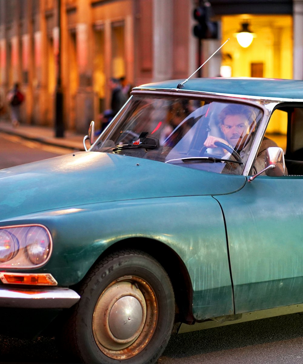 a man driving a green car down a street