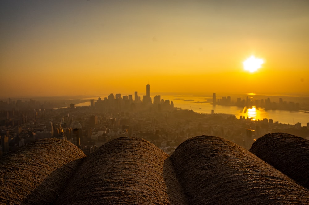 the sun is setting over a city and a body of water