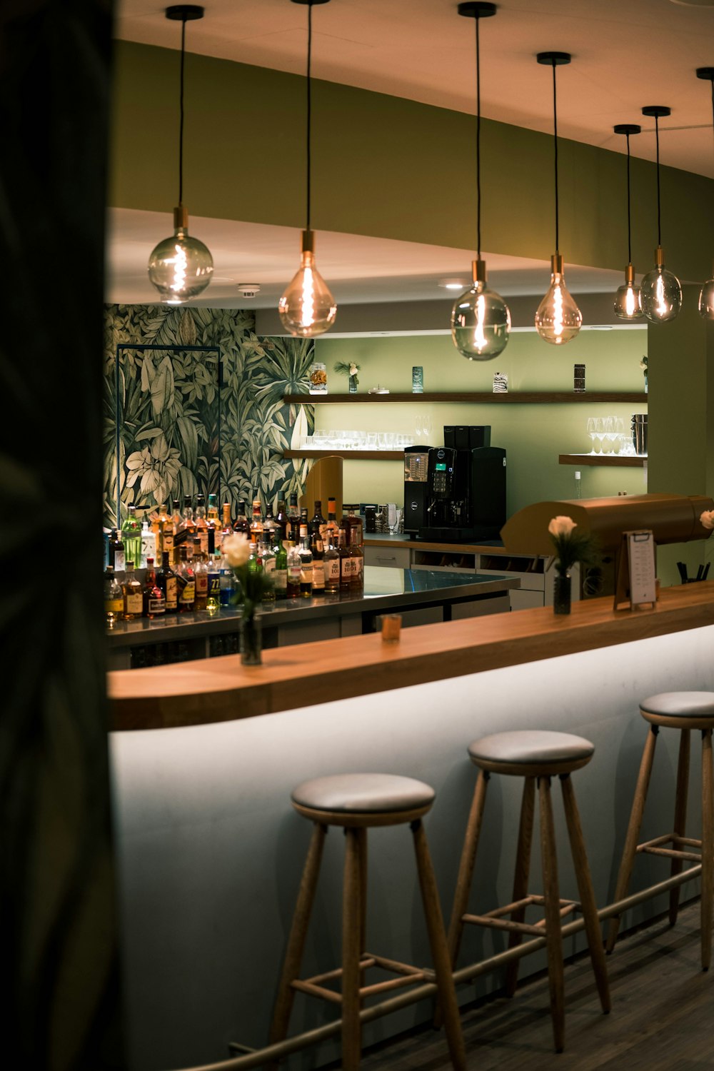 a bar with stools and lights hanging from the ceiling